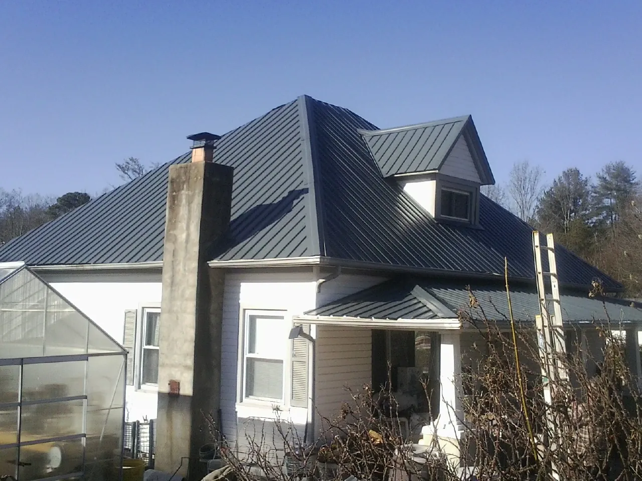 Dark blue standing seam metal roof on a white farmhouse with dormer — Slate & Tile Roof Repair by Roofing Brothers in La Grande