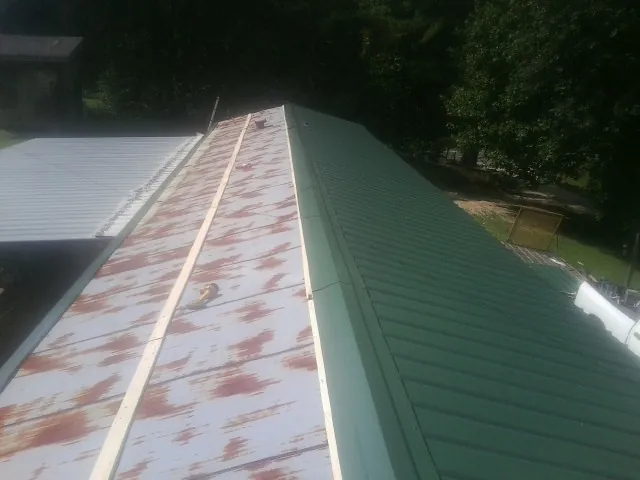 Old rusted panels beside newly installed green metal roofing — Wind Damage Roof Repair by Roofing Brothers in La Grande