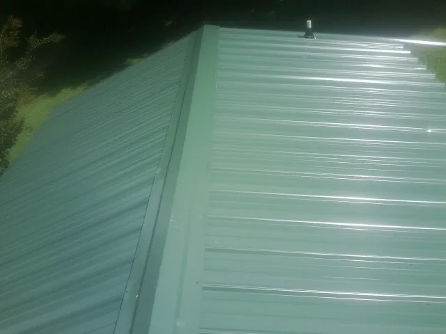 New green metal panels meeting at the ridge of a roof — Flat Roof Repair work by our crew in La Grande