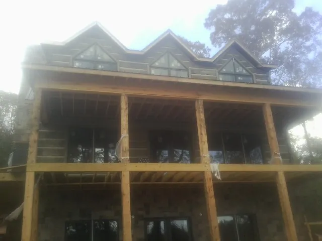 Dormers and porch framing on a large log home under construction — Roof Coating work by our crew in La Grande