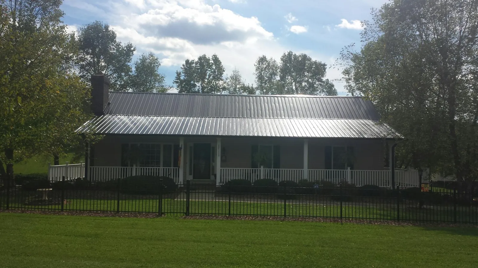 Gray metal roof on a brick ranch with a full width front porch — Gutter Guard Installation work by our crew in La Grande