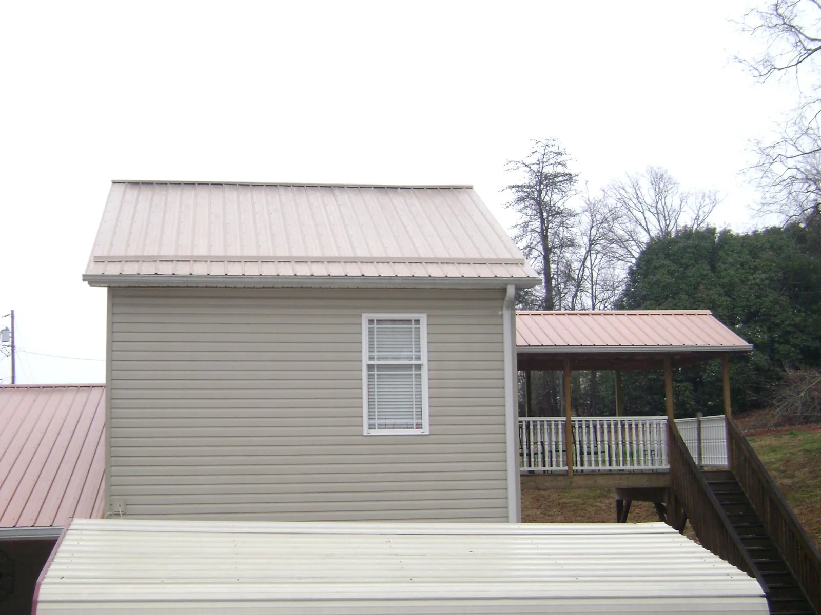 Tan metal roofs on a two story addition and attached porch, from a Roof Replacement job in La Grande