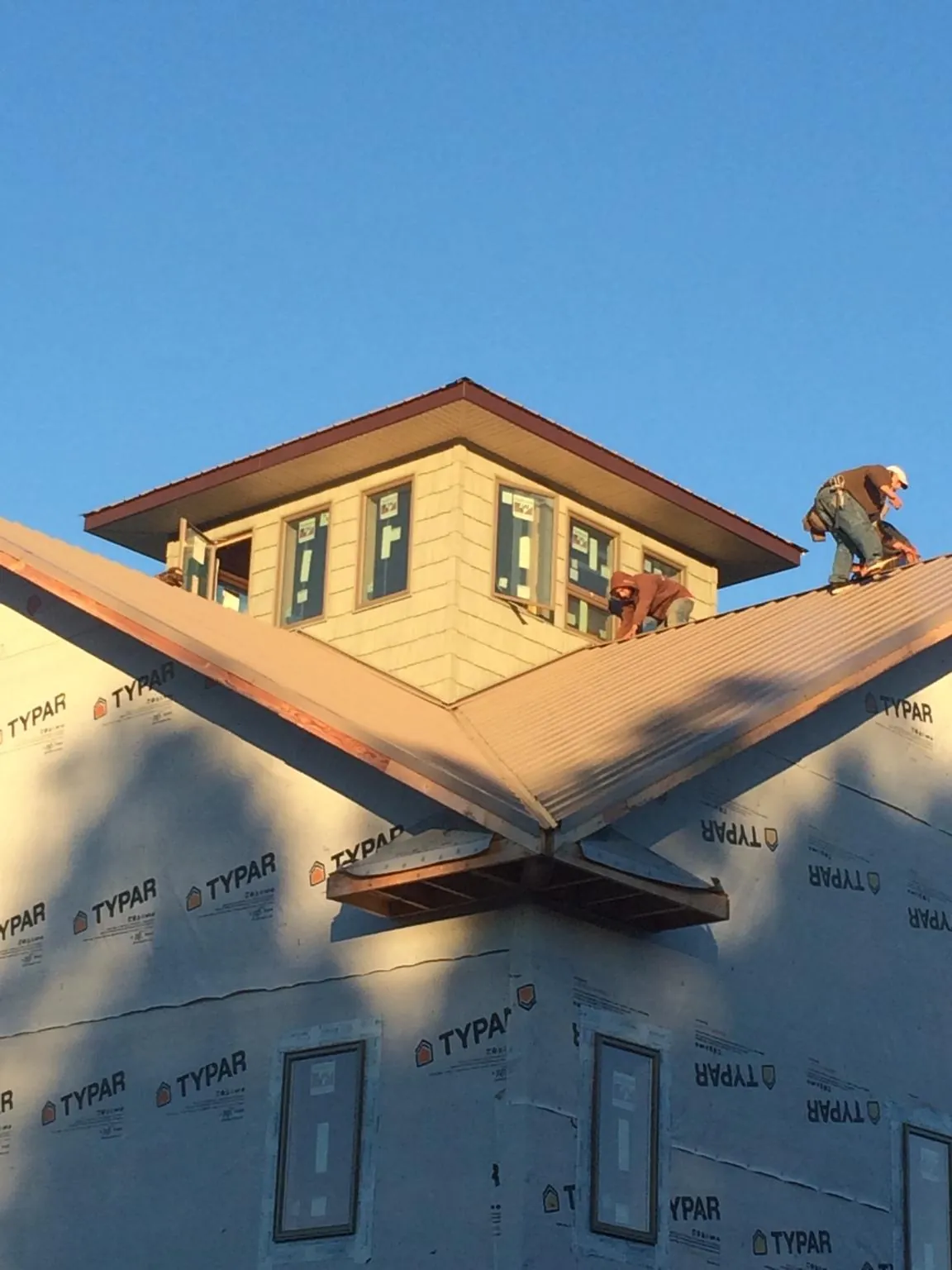 Roofers working around a rooftop cupola on a new metal roof at sunset — Roof Waterproofing in La Grande by Roofing Brothers